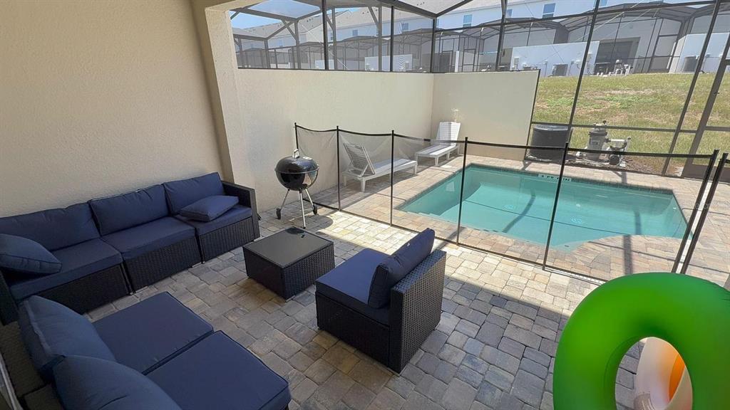 A patio with outdoor furniture and a grill overlooks a small screened-in swimming pool — 2334 ZABALLINA PLACE UNIT 2343, KISSIMMEE, FL