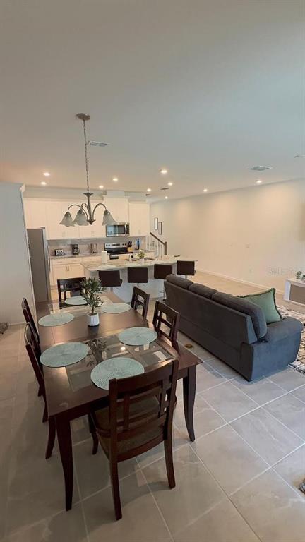 A dining area with a wooden table and chairs sits in front of an open kitchen — 2334 ZABALLINA PLACE UNIT 2343, KISSIMMEE, FL
