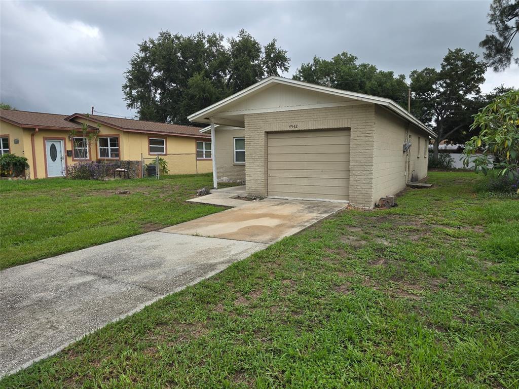 A single-story tan brick house with an attached garage and a concrete driveway — 4542 21ST AVENUE S, ST PETERSBURG, FL