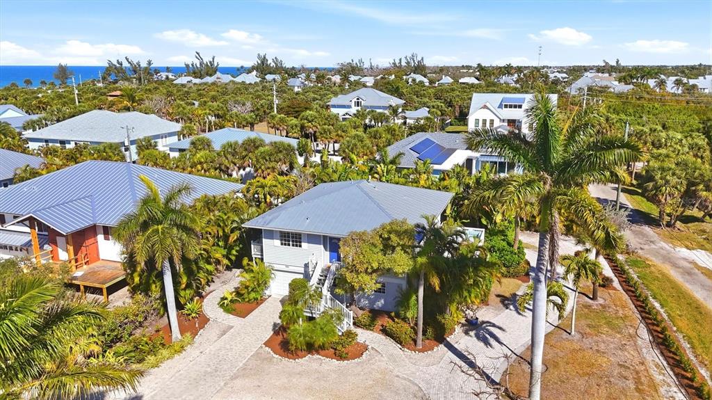 An aerial view shows a residential neighborhood with several houses surrounded by lush tropical vegetation — 281 SEABREEZE COURT, BOCA GRANDE, FL