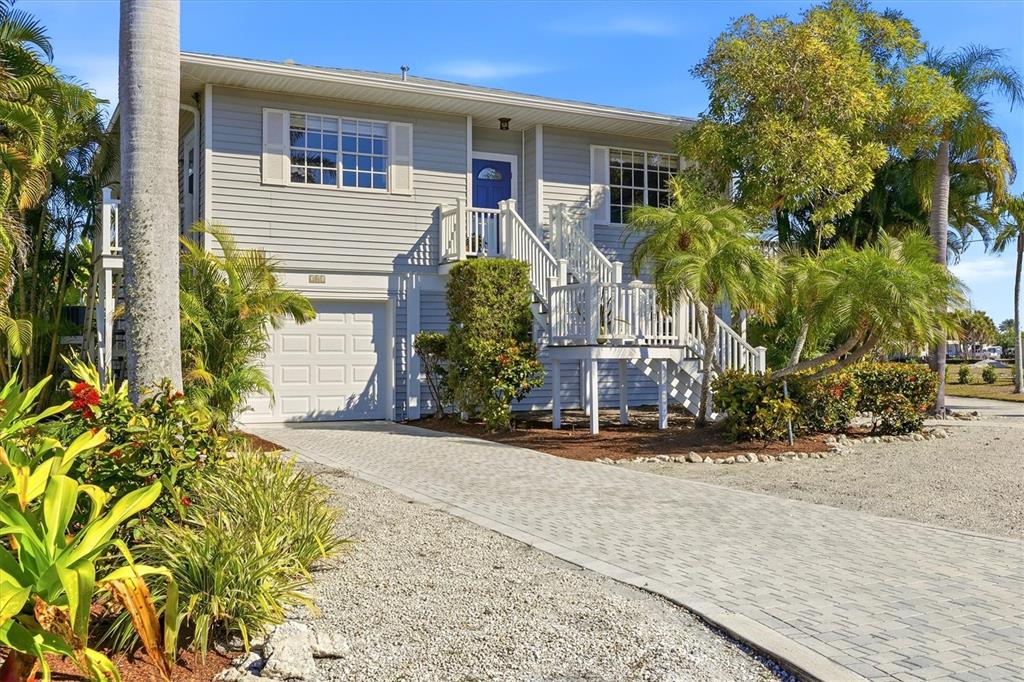 A two-story house with light gray siding, a white garage door, and an elevated entryway — 281 SEABREEZE COURT, BOCA GRANDE, FL