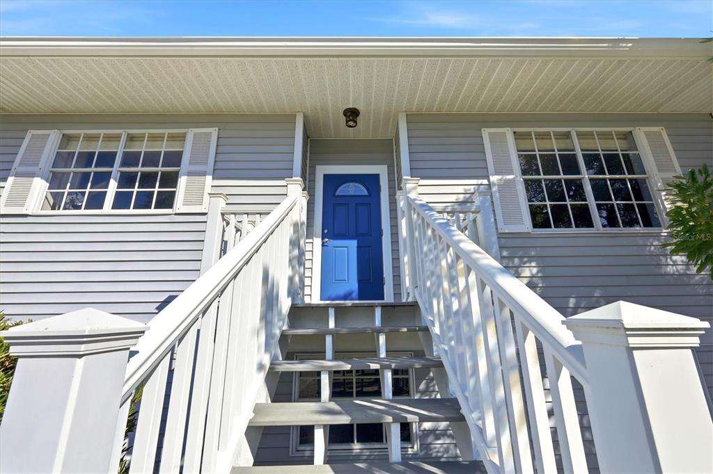 A blue front door is accessed by a wooden staircase with white railings — 281 SEABREEZE COURT, BOCA GRANDE, FL