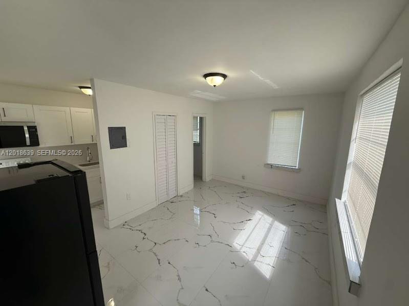 A kitchen and dining area with white marble-patterned tile floors and white walls — 2775 NW 57th St, Miami FL 33142, MIAMI, FL
