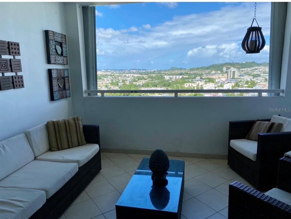 A balcony with wicker furniture, a coffee table, and a panoramic view of a city — 155 CARAZO ST. CONDO. REGENCY PARK UNIT 17-C, GUAYNABO, PR