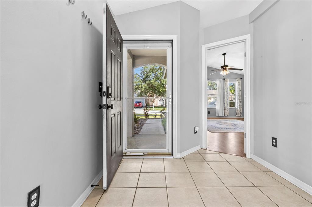 An entryway with tiled flooring, a dark front door, and a view into a living room — 1239 AVONWOOD COURT, LUTZ, FL