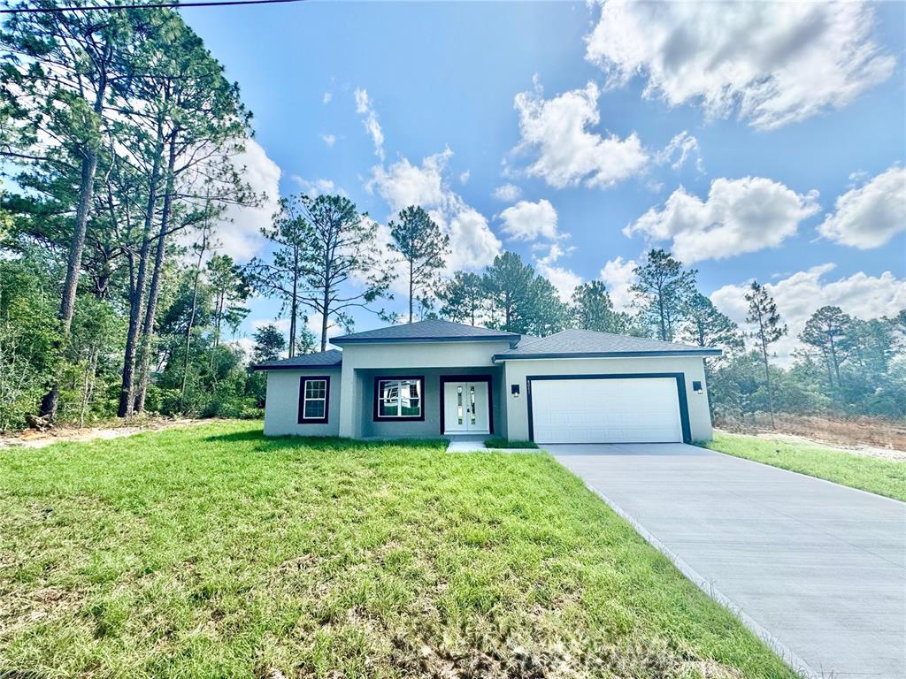 A single-story house with a white garage, gray exterior, and a concrete driveway — 8051 N PINKINZ WAY, CITRUS SPRINGS, FL