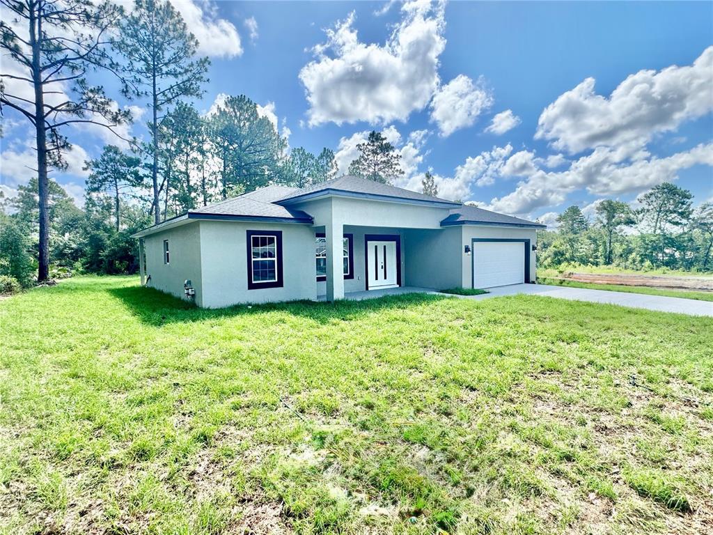 A single-story house with a gray stucco exterior, dark window frames, and an attached garage — 8051 N PINKINZ WAY, CITRUS SPRINGS, FL