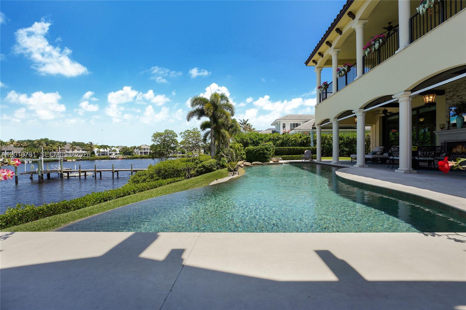 An infinity pool overlooks a canal with a private dock and a two-story house — 10433 SE Banyan Way, Jupiter FL 33469, JUPITER, FL