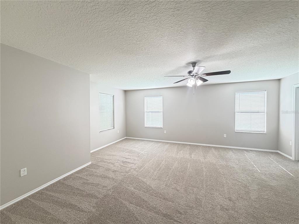 A bedroom features a bed, a wooden dresser, two white chairs, and a ceiling fan — 14629 BAHAMA SWALLOW BOULEVARD, WINTER GARDEN, FL