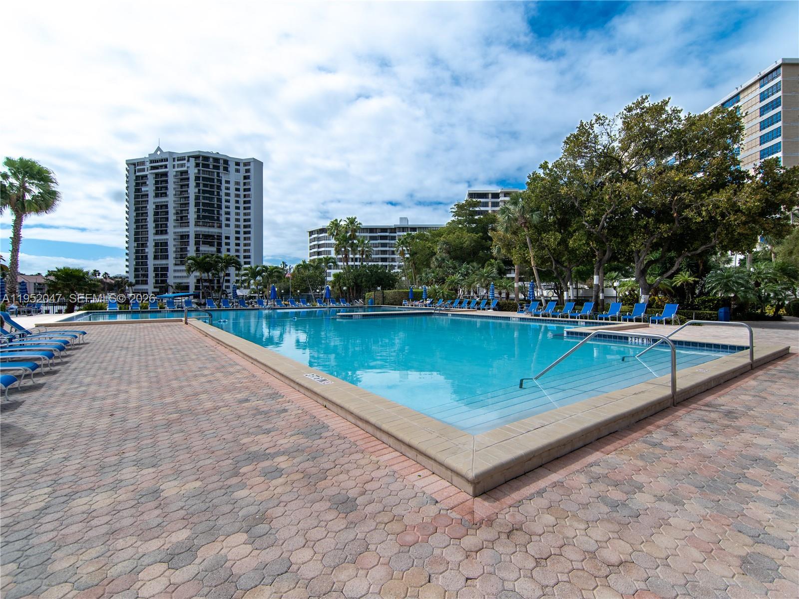 A large rectangular swimming pool is surrounded by a paved deck and lounge chairs — 2500 Parkview Dr # 2312, Hallandale Beach FL 33009, HALLANDALE BEACH, FL