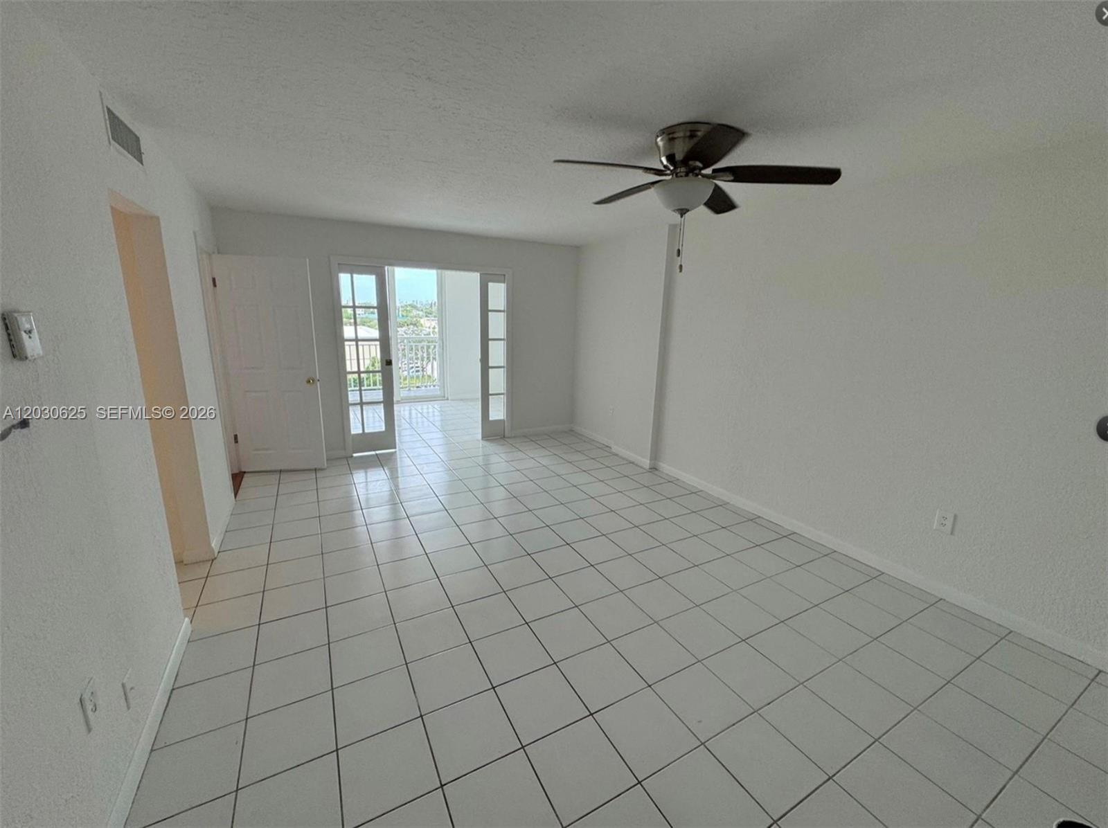 An empty room with white walls, white tile flooring, a ceiling fan, and a balcony door — 1251 NE 108th St # 409, Miami FL 33161, MIAMI, FL