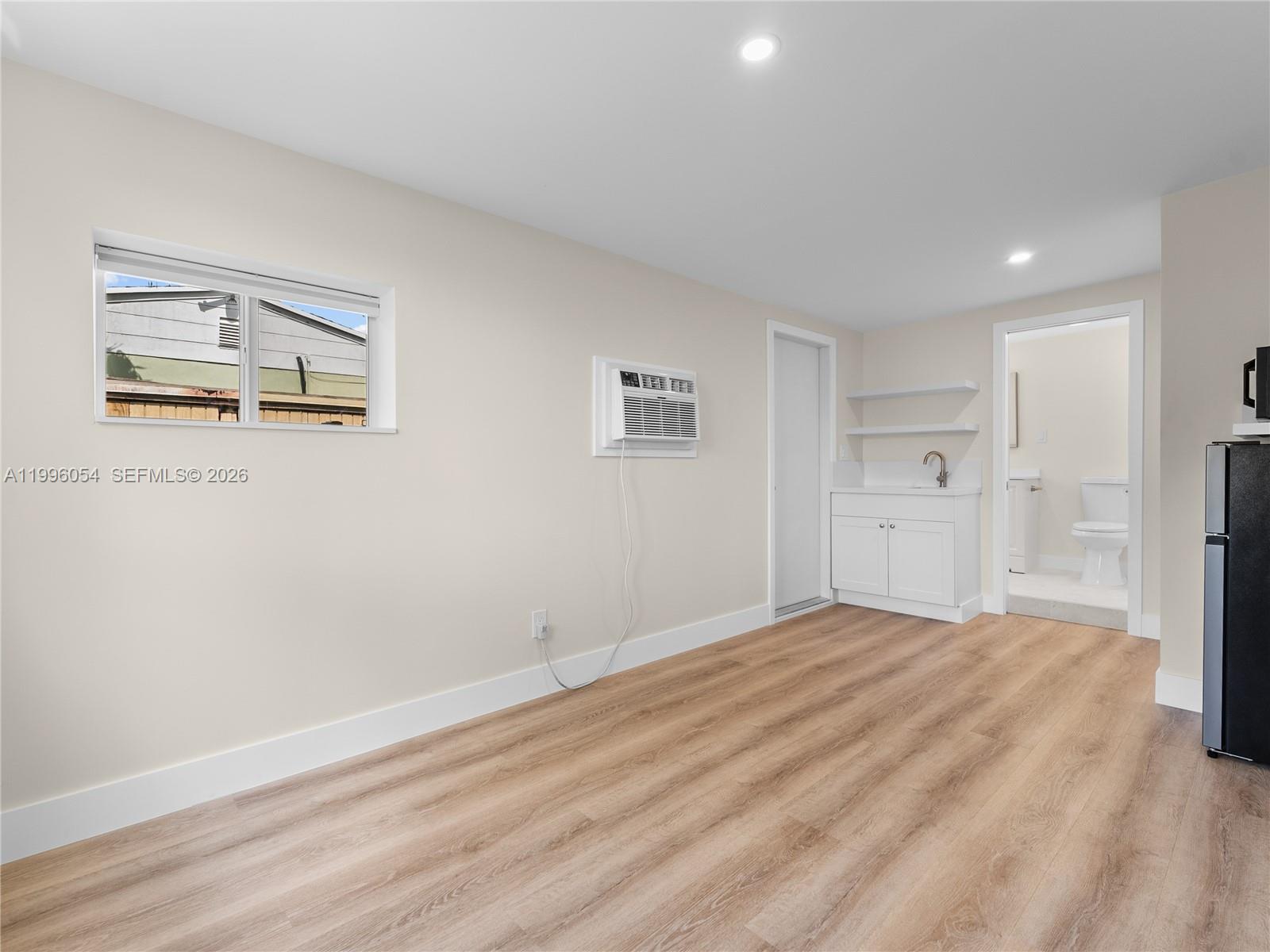 A room with light wood-look flooring, a window air conditioner, a small kitchenette, and bathroom — 7401 SW 38th St # A, Miami FL 33155, MIAMI, FL