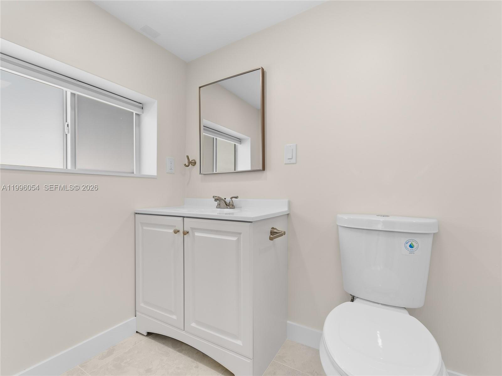 A bathroom features a white vanity, a rectangular mirror, and a white toilet — 7401 SW 38th St # A, Miami FL 33155, MIAMI, FL