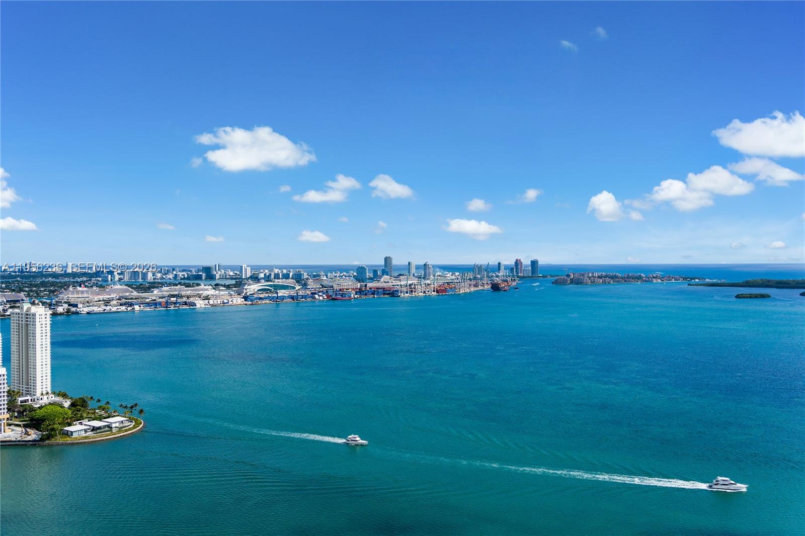 An aerial view shows a blue bay with boats, a port, and a distant city skyline — 1331 Brickell Bay Dr, Miami FL 33131, MIAMI, FL