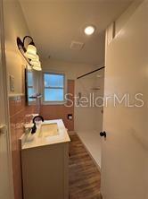 A bathroom features a vanity with a sink, a walk-in shower, and pink wall tiles — 912 LAKE JESSIE DRIVE, WINTER HAVEN, FL