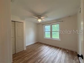 A bedroom with light-colored walls, wood-look flooring, a ceiling fan, and a sliding closet door — 912 LAKE JESSIE DRIVE, WINTER HAVEN, FL