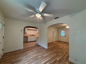 An interior view shows a living area with wood-look flooring, a ceiling fan, and arched doorways — 912 LAKE JESSIE DRIVE, WINTER HAVEN, FL