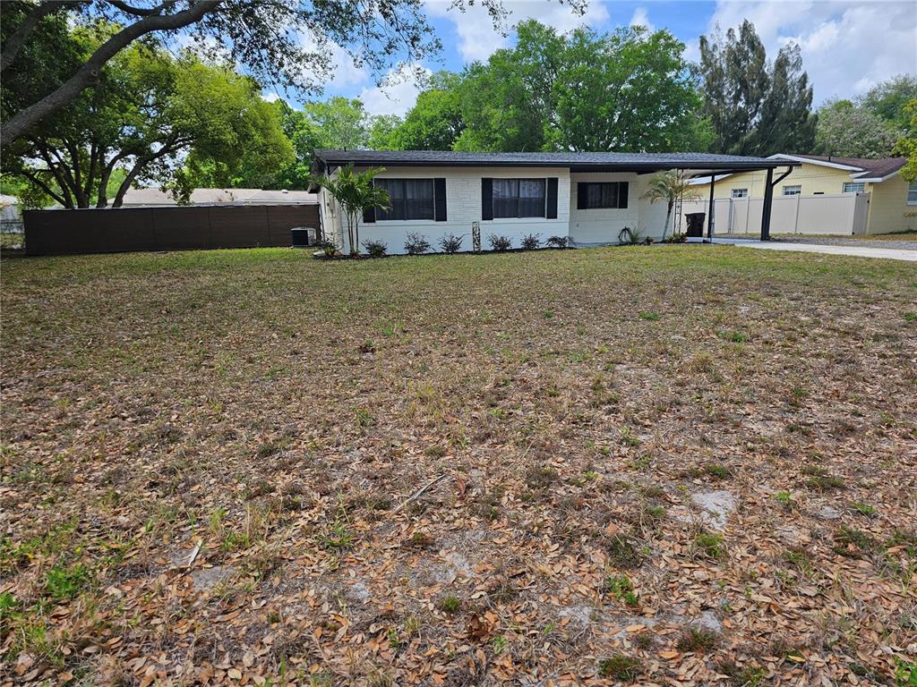 A single-story house with a white brick exterior and a carport sits on a lot — 1120 SAN LUIS DRIVE, ORLANDO, FL