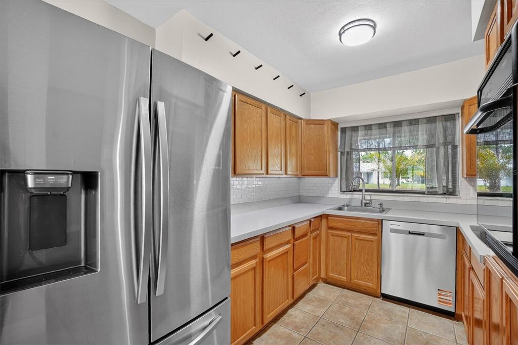 A kitchen features stainless steel appliances, oak cabinets, a white subway tile backsplash, and tile flooring — 1120 SAN LUIS DRIVE, ORLANDO, FL