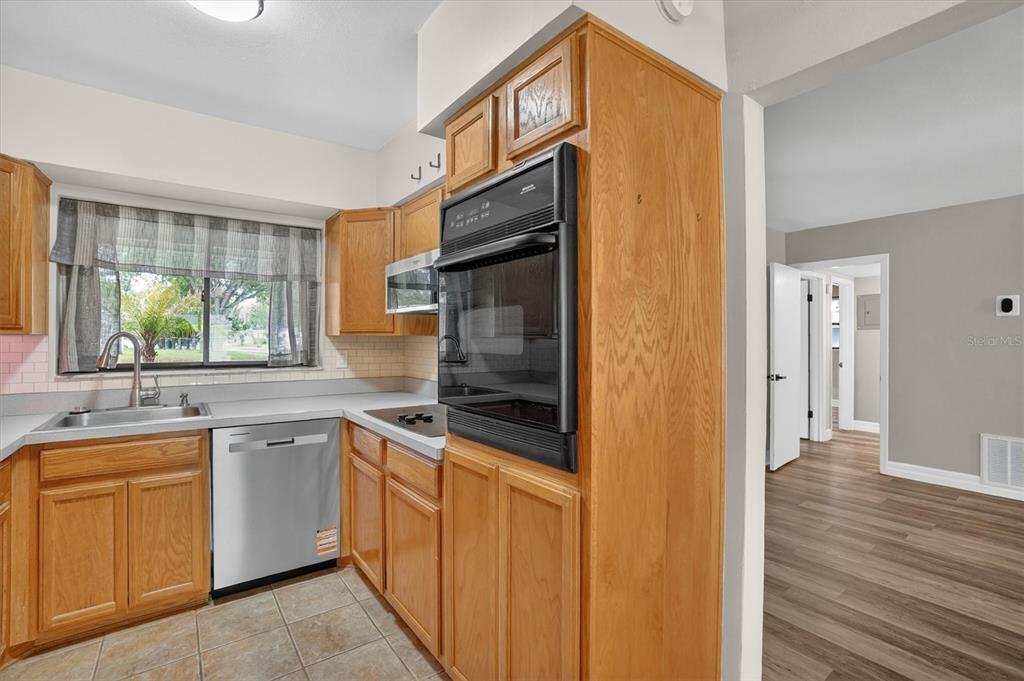A kitchen with wood cabinets, stainless steel appliances, and a window above the sink — 1120 SAN LUIS DRIVE, ORLANDO, FL