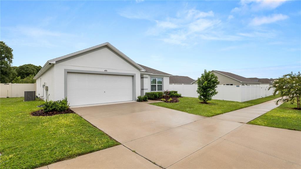 A single-story house with a white exterior, a two-car garage, and a concrete driveway — 4791 DRAKE AVENUE, LAKELAND, FL