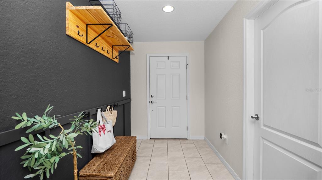 An entryway features a black accent wall with a wooden shelf, coat hooks, and a bench — 4791 DRAKE AVENUE, LAKELAND, FL
