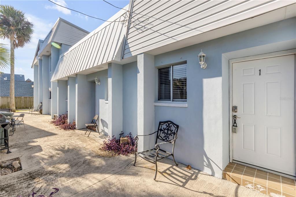 A light blue building exterior features a white front door labeled with the number one — 410 BUTLER BOULEVARD, DAYTONA BEACH, FL