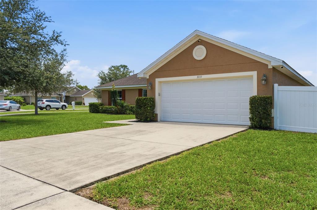 A tan house with a two-car garage and a concrete driveway under a blue sky — 3777 FANTASY WAY, BROOKSVILLE, FL