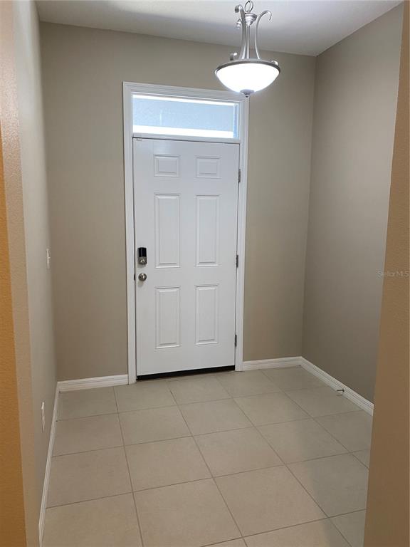 An entryway features a white door with a transom window, tile flooring, and a light fixture — 8642 FALLING BLUE PLACE, RIVERVIEW, FL