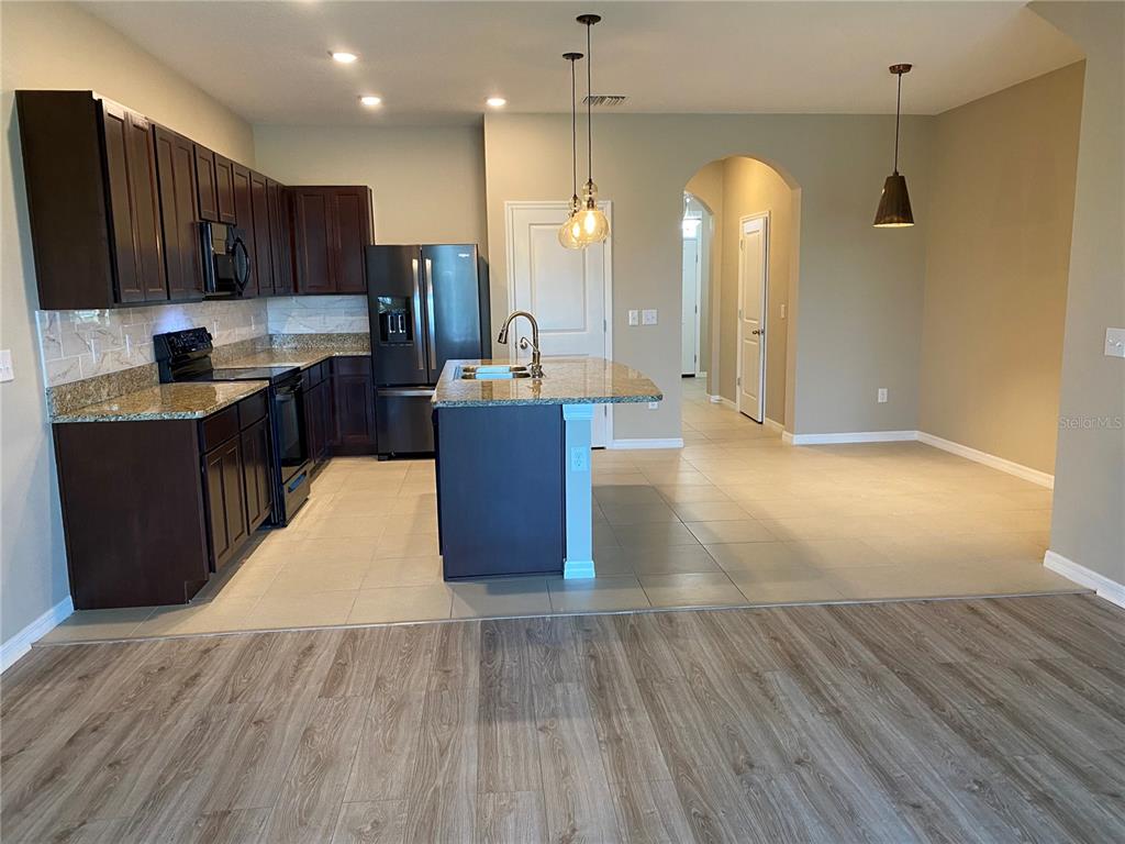 A kitchen with dark wood cabinets, granite countertops, a center island, and tile flooring — 8642 FALLING BLUE PLACE, RIVERVIEW, FL