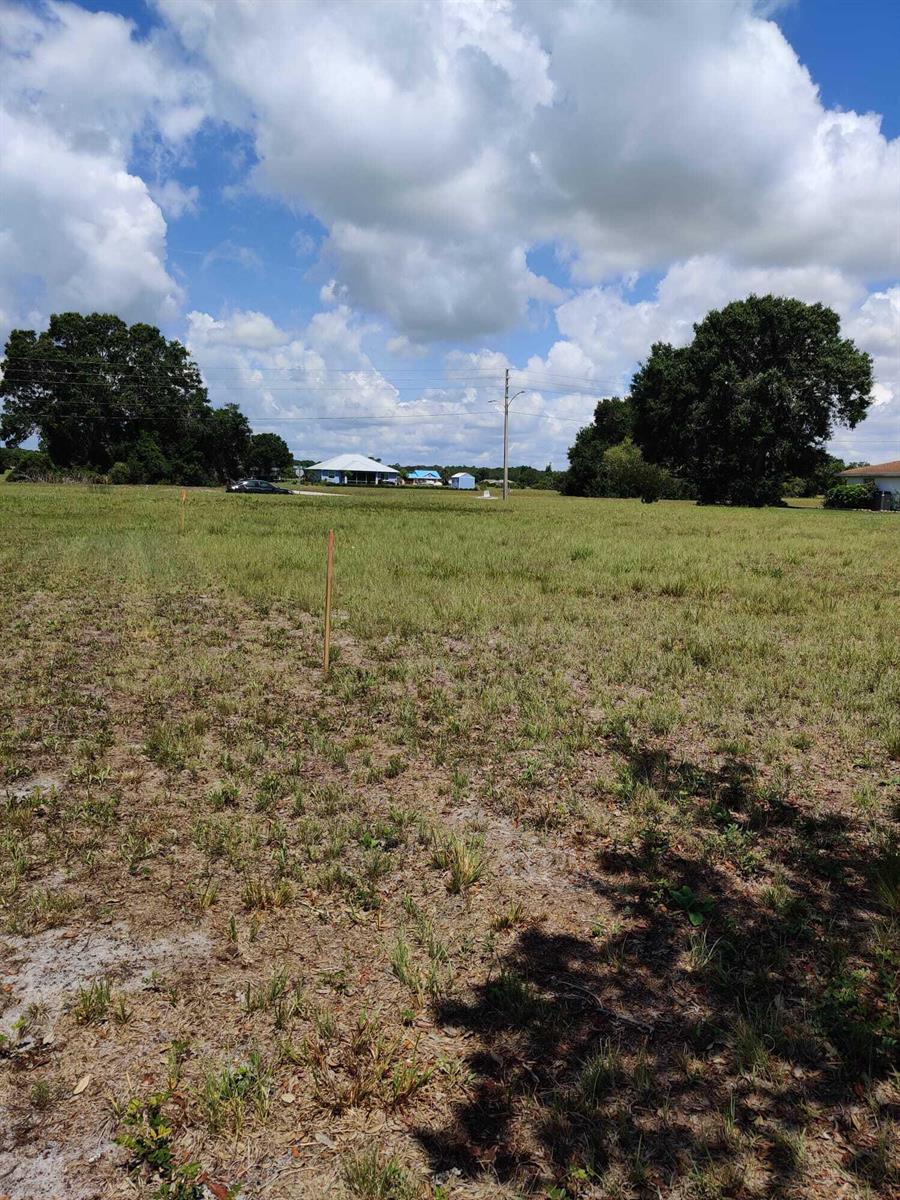 A wide, grassy vacant lot features scattered wooden survey stakes under a bright blue sky — 225 Monte Real Boulevard, Sebring FL 33876, SEBRING, FL