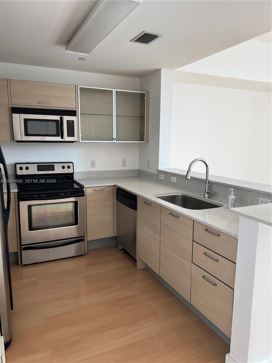 A kitchen features light wood cabinets, stainless steel appliances, and a gray countertop — 350 NE 24th St # 407, Miami FL 33137, MIAMI, FL