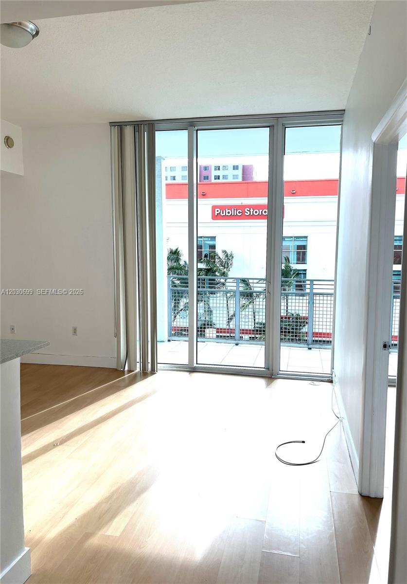 This room features light wood flooring, white walls, and a sliding glass door to a balcony — 350 NE 24th St # 407, Miami FL 33137, MIAMI, FL