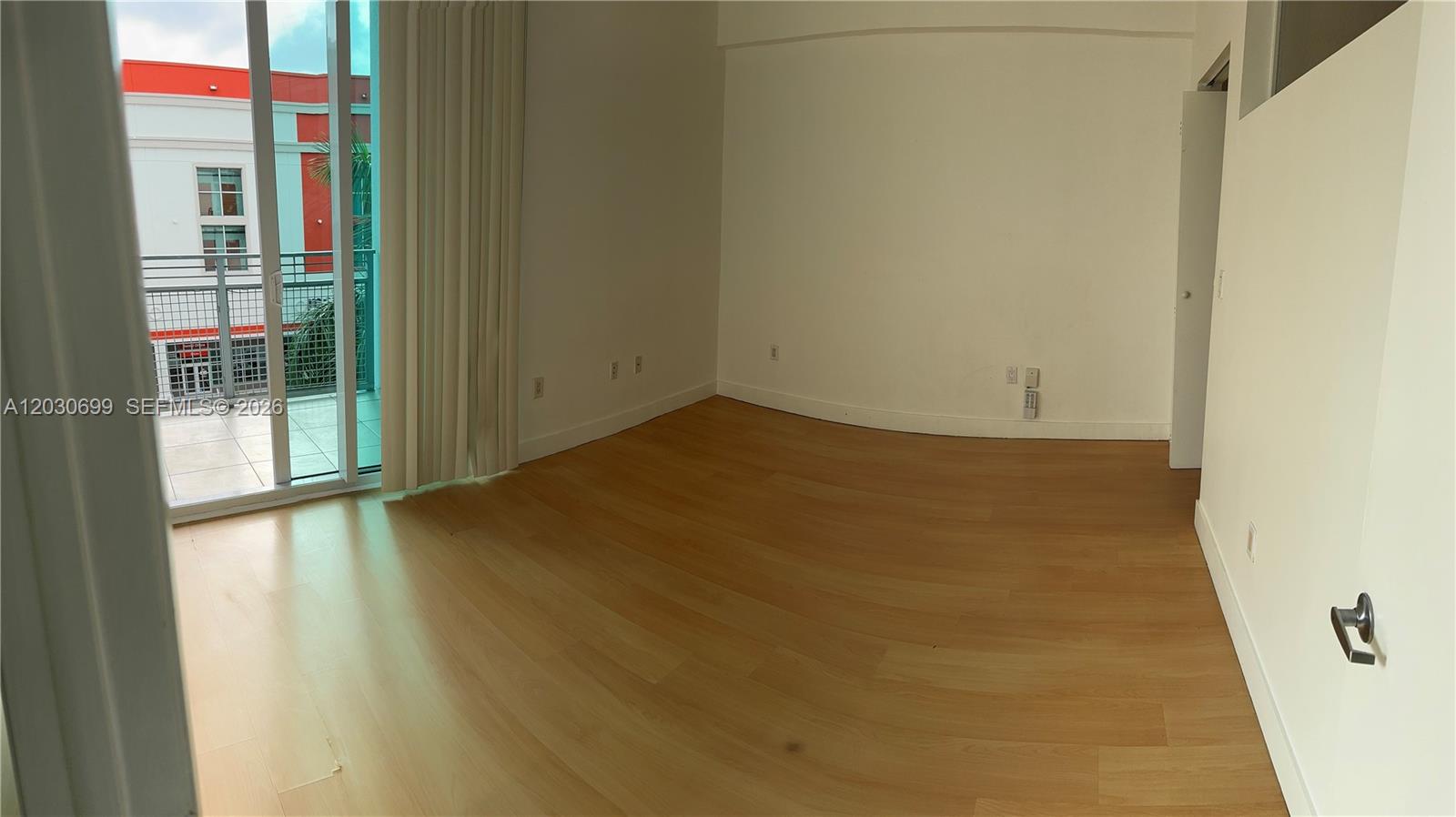 An empty room features light wood flooring, white walls, and a sliding glass door to a balcony — 350 NE 24th St # 407, Miami FL 33137, MIAMI, FL