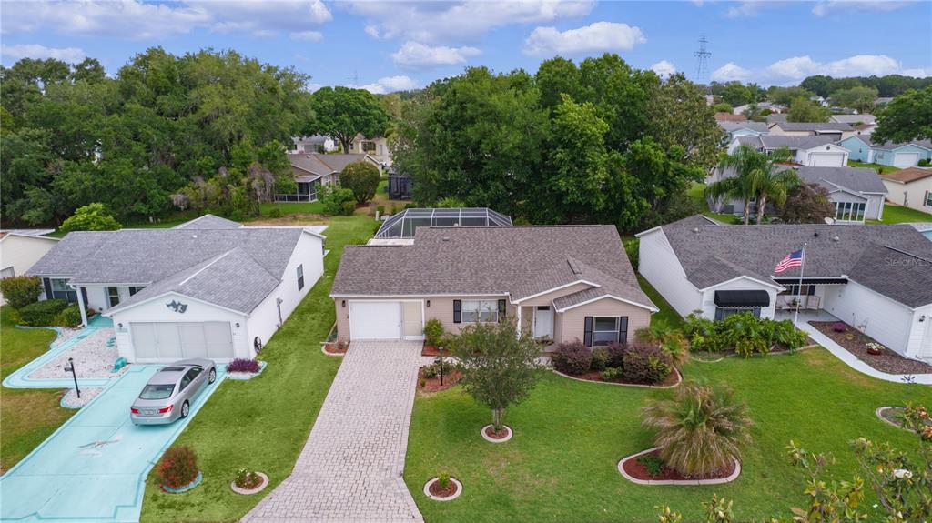 An aerial view of a single-story suburban house with a paved driveway and pool enclosure — 1411 JUAREZ PLACE, THE VILLAGES, FL