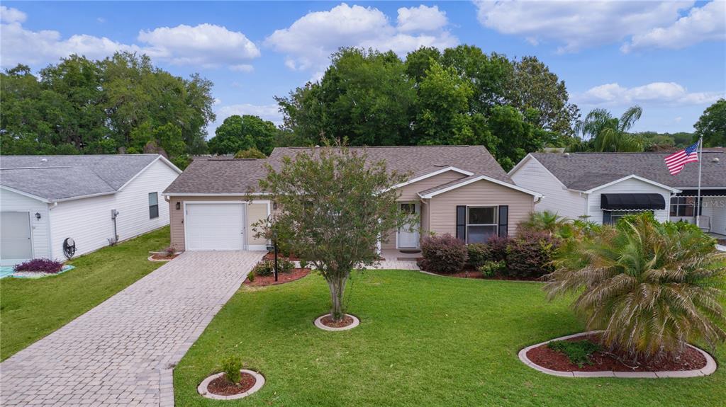 A single-story house with a paved driveway, a front lawn, and a light-colored exterior — 1411 JUAREZ PLACE, THE VILLAGES, FL