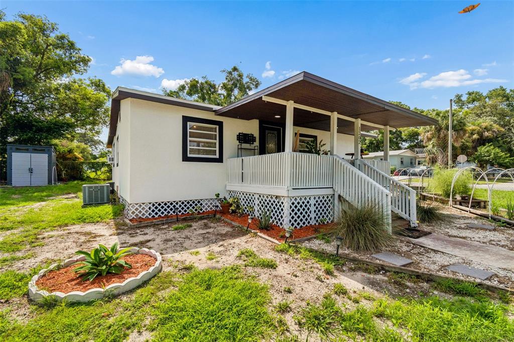 A single-story house with a covered front porch, white siding, and a lattice foundation — 1202 E ANNIE STREET, TAMPA, FL