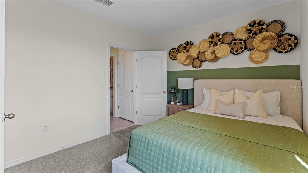 A bedroom features a green accent wall, a bed with a green quilt, and wall-mounted baskets — 2614 ANGEL FALLS DRIVE, DAVENPORT, FL