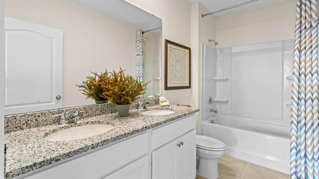A bathroom features a double vanity with granite countertops, white cabinets, and a shower-tub combo — 2614 ANGEL FALLS DRIVE, DAVENPORT, FL