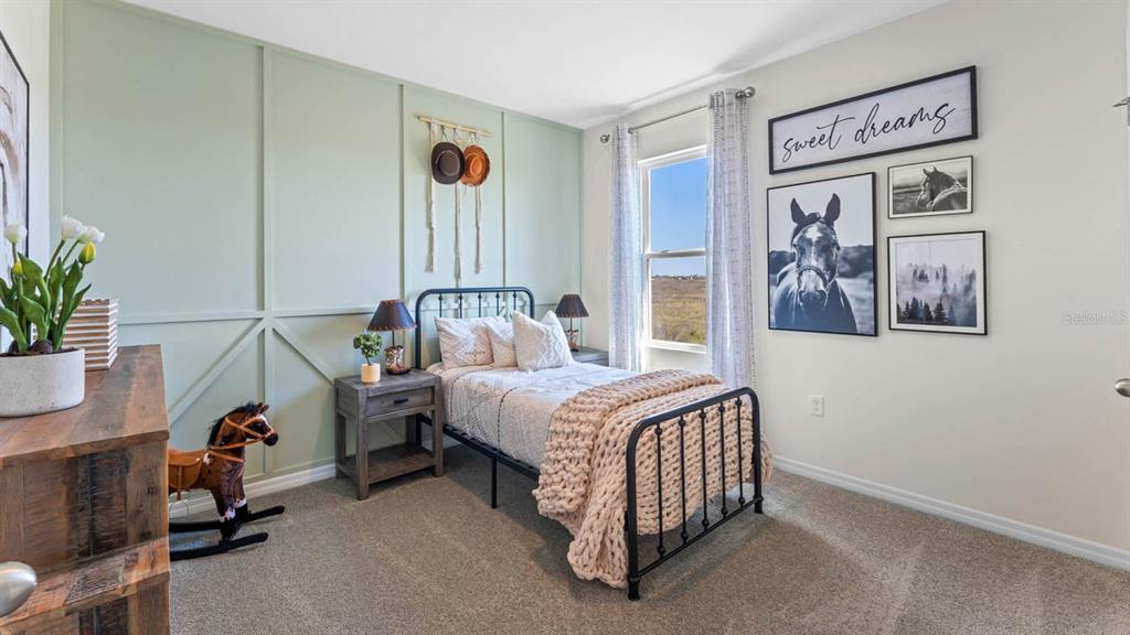 A bedroom features a sage green accent wall, a metal bed frame, and horse-themed decor — 2614 ANGEL FALLS DRIVE, DAVENPORT, FL
