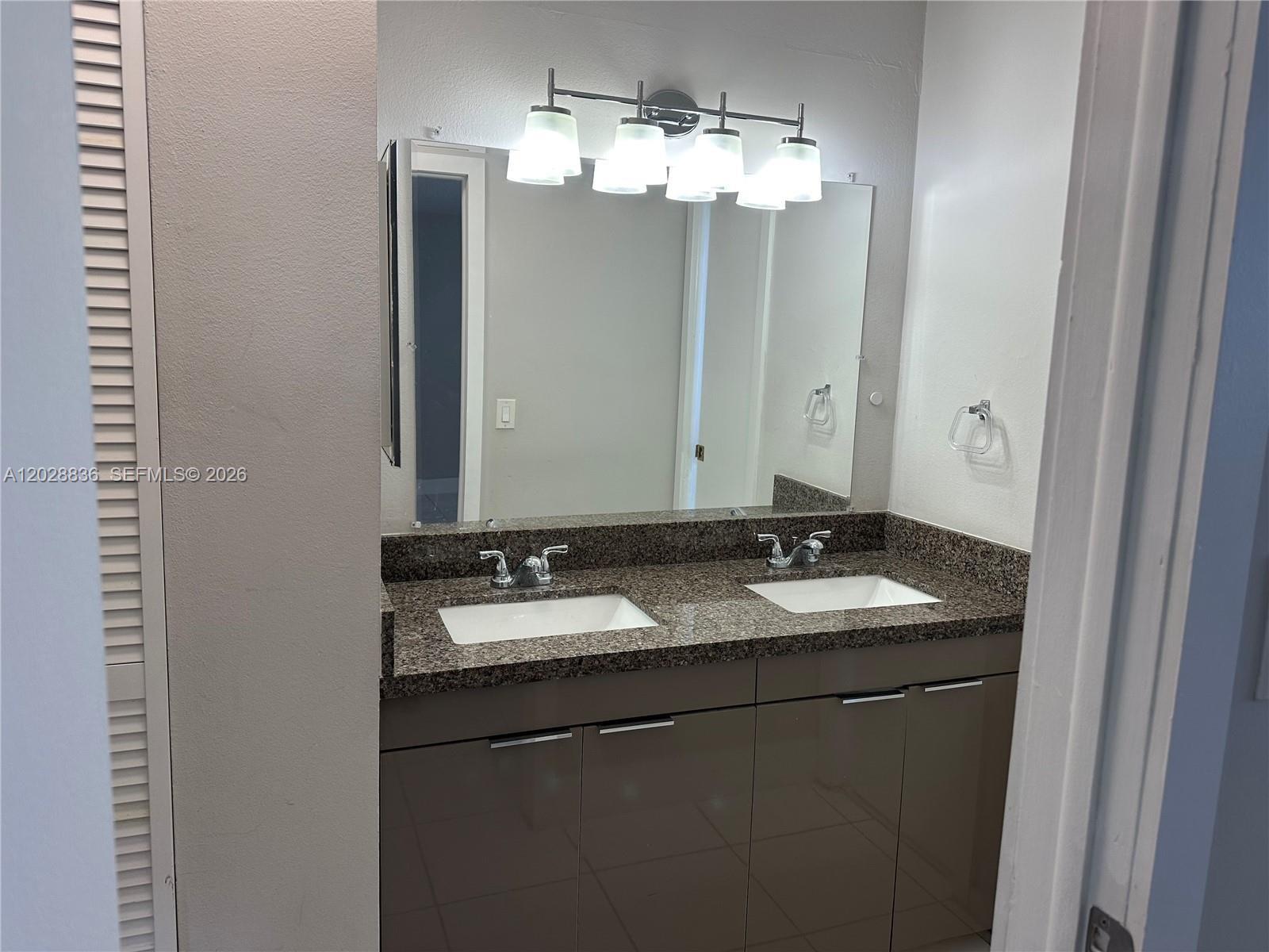 A bathroom features a double vanity with a granite countertop and a four-light fixture — 1975 NE 135th St # 3E, North Miami FL 33181, NORTH MIAMI, FL