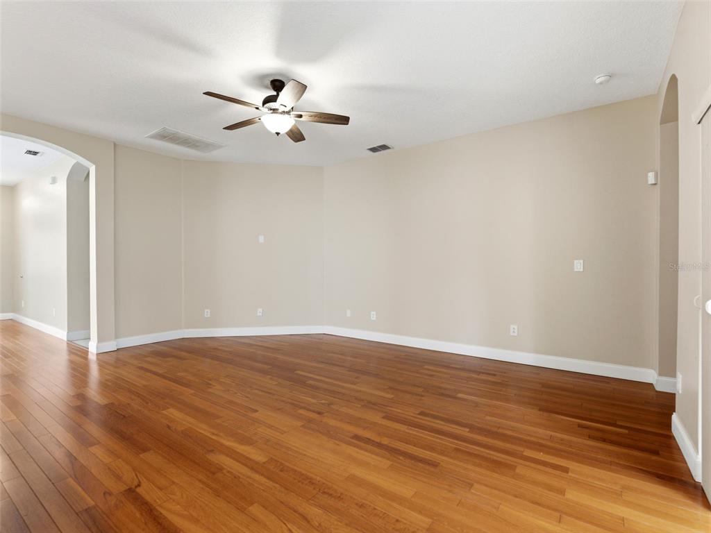 An empty room with hardwood floors, beige walls, and a ceiling fan — 23802 CORAL RIDGE LANE, LAND O LAKES, FL