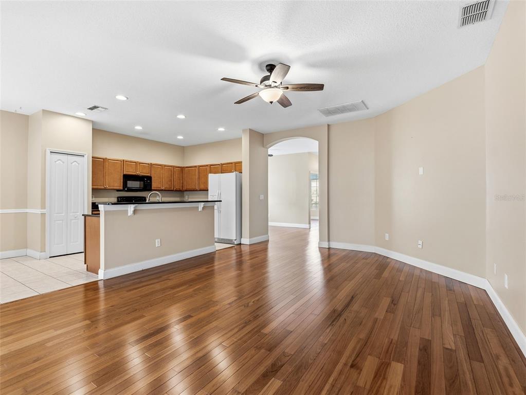 A kitchen with wood cabinets and a breakfast bar opens into a spacious living area — 23802 CORAL RIDGE LANE, LAND O LAKES, FL