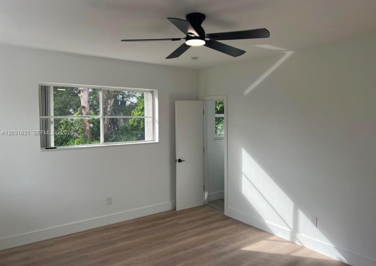 A bedroom features light wood-look flooring, white walls, a ceiling fan, and a window — 7730 Byron Ave # 4, Miami Beach FL 33141, MIAMI BEACH, FL