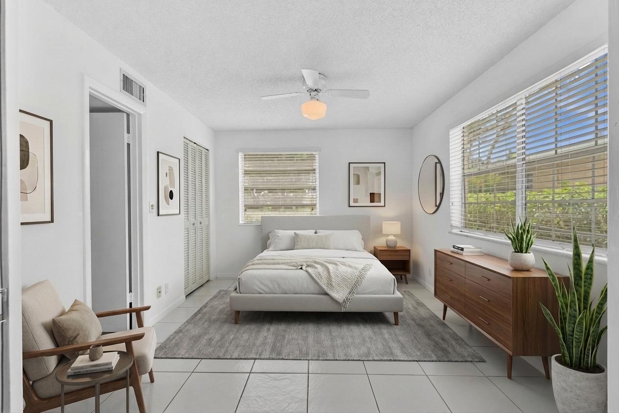 A bedroom with a bed, dresser, armchair, and tile flooring, featuring a ceiling fan — 13721 Flora Place # D, Delray Beach FL 33484, DELRAY BEACH, FL