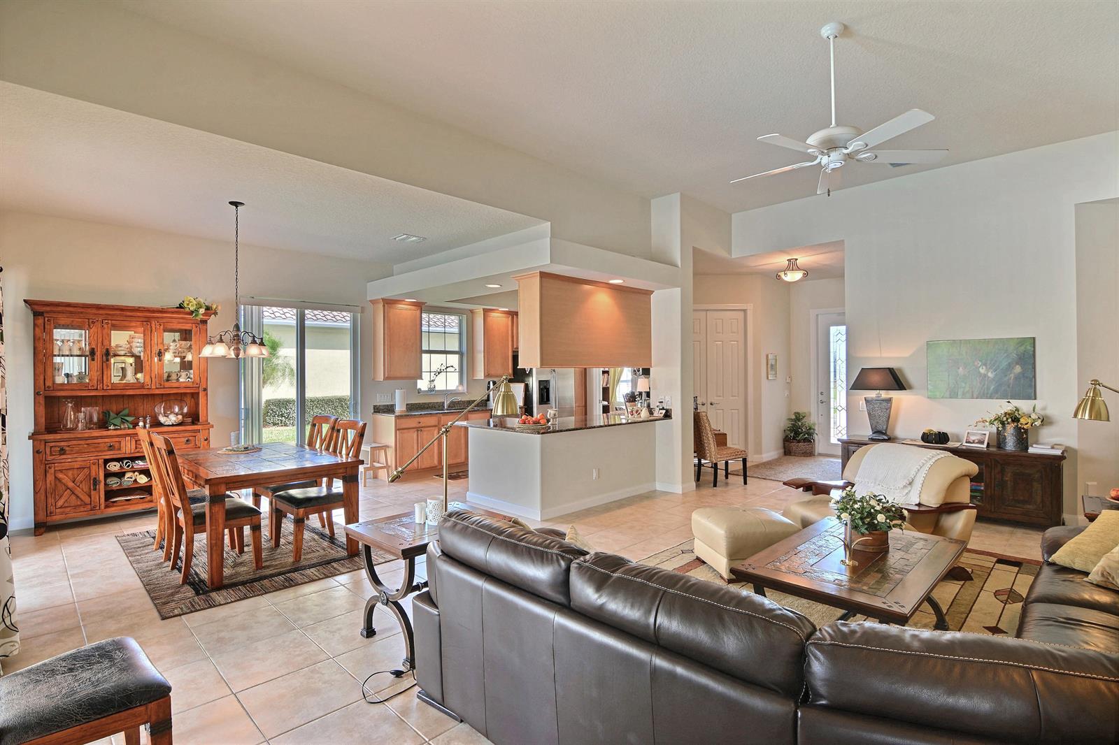An open-concept living and dining area with tile floors, wooden cabinetry, and a ceiling fan — 5254 Eleuthra Circle, Vero Beach FL 32967, VERO BEACH, FL