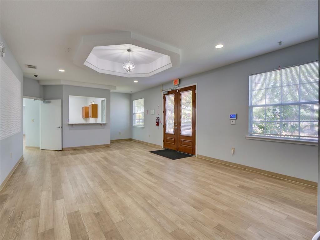 A spacious room with light wood-look flooring, a tray ceiling, and double glass-paneled doors — 733 S GOLDENROD ROAD, ORLANDO, FL