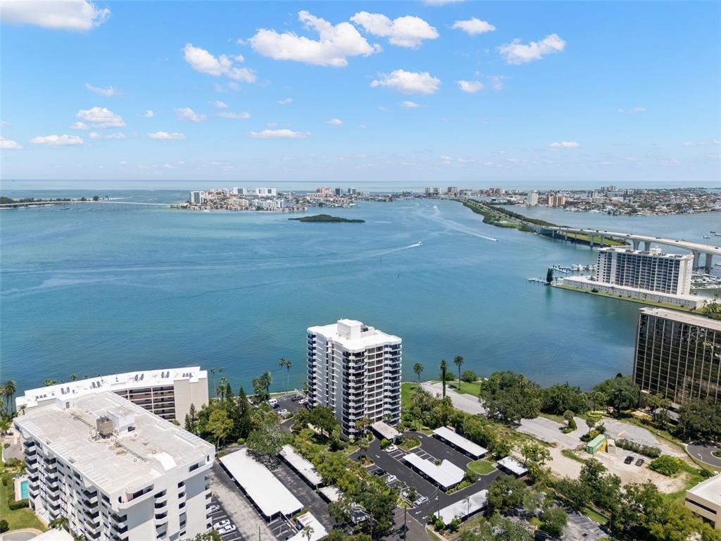 An aerial view shows several high-rise apartment buildings situated along a bay with bridges — 80 ROGERS STREET UNIT 3A, CLEARWATER, FL