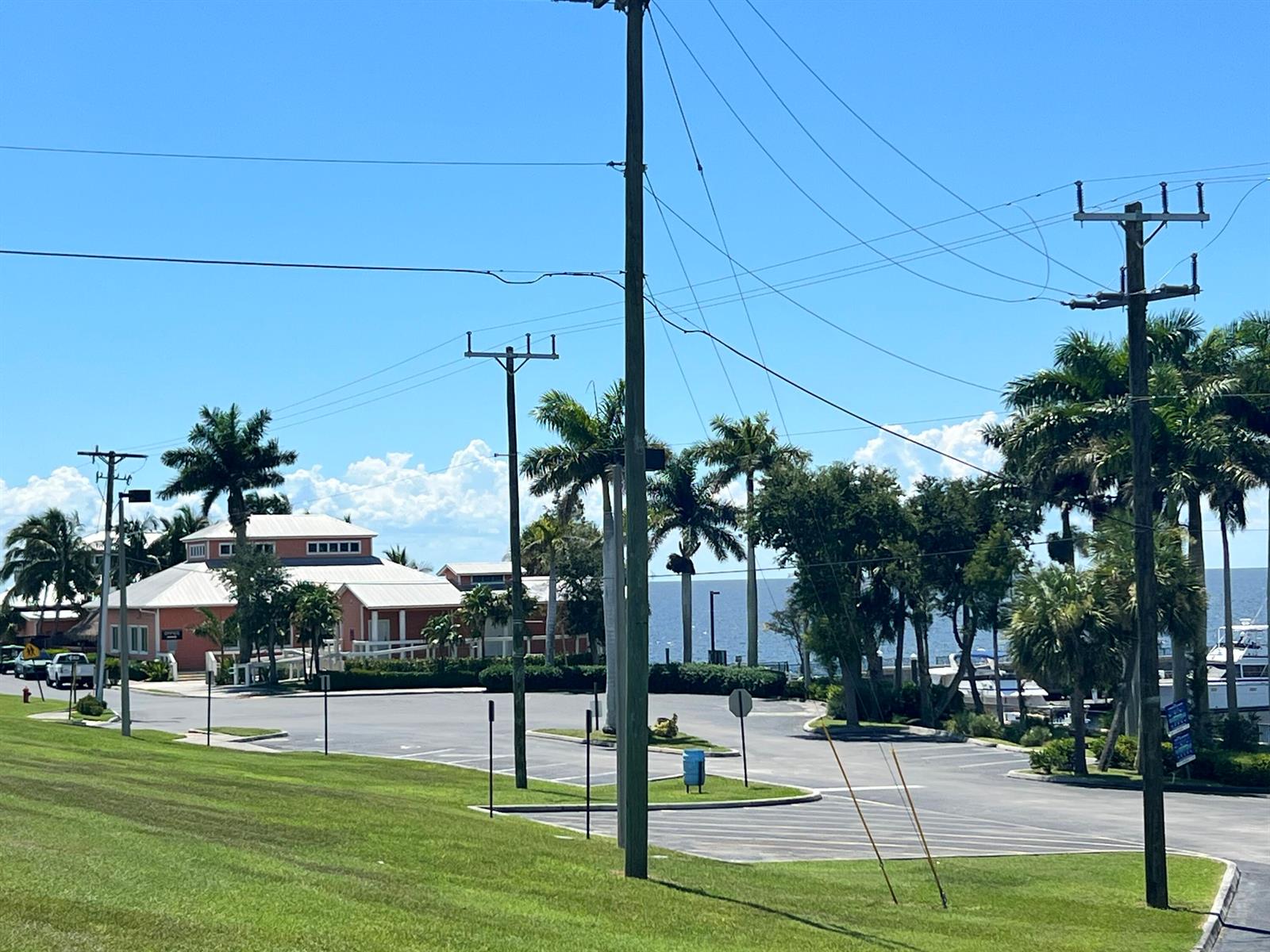 A parking lot sits in front of a pink building near the ocean with palm trees — 197 W Main Street, Pahokee FL 33476, PAHOKEE, FL
