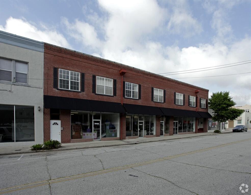 A two-story brick commercial building with storefront windows and black awnings along the street — 21 MAIN STREET, TITUSVILLE, FL